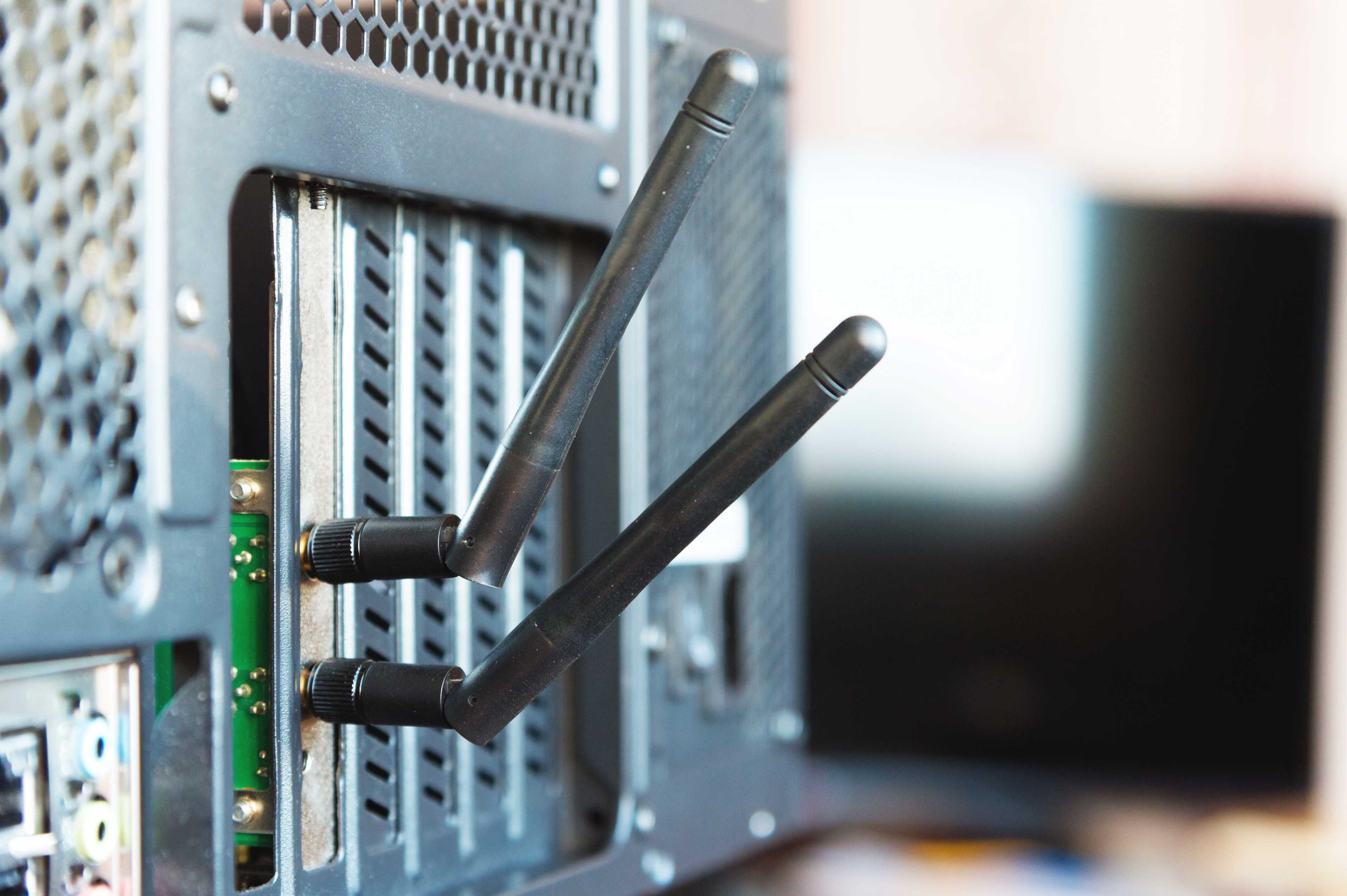 A close-up image of the back of a desktop computer showing two black Wi-Fi antennas attached to a network card